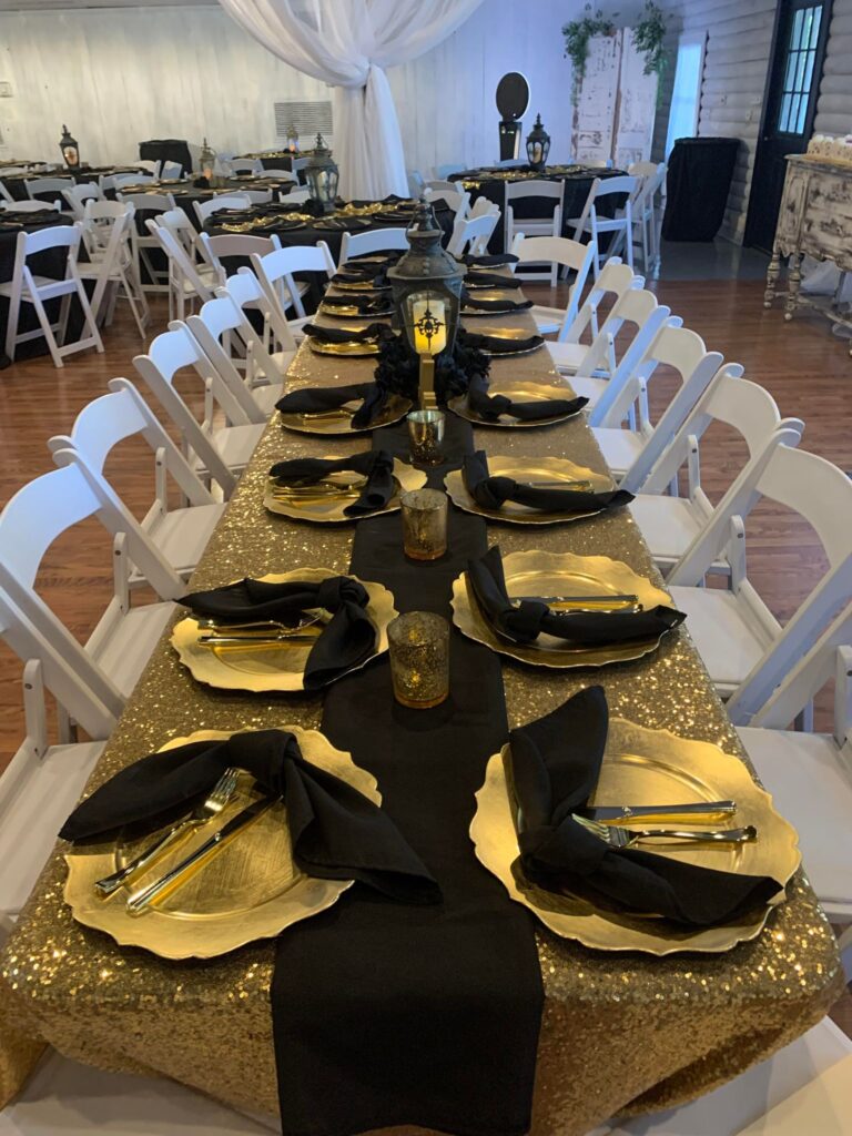 Gold sequin banquet table with black napkins and lantern centerpiece